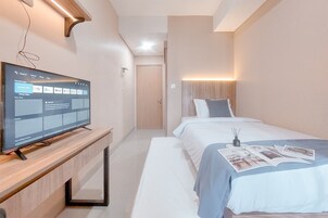 A hotel room with a bed, bedside table, and a flat-screen TV displaying a streaming service interface.