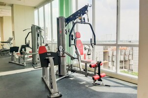 A gym with exercise equipment, large windows, and a view of the city.