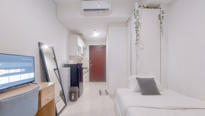 A modern hotel room with a TV, a desk, a bed, and a bathroom. - Modern Look Studio at Springwood Residence Tangerang Apartment (Tangerang)