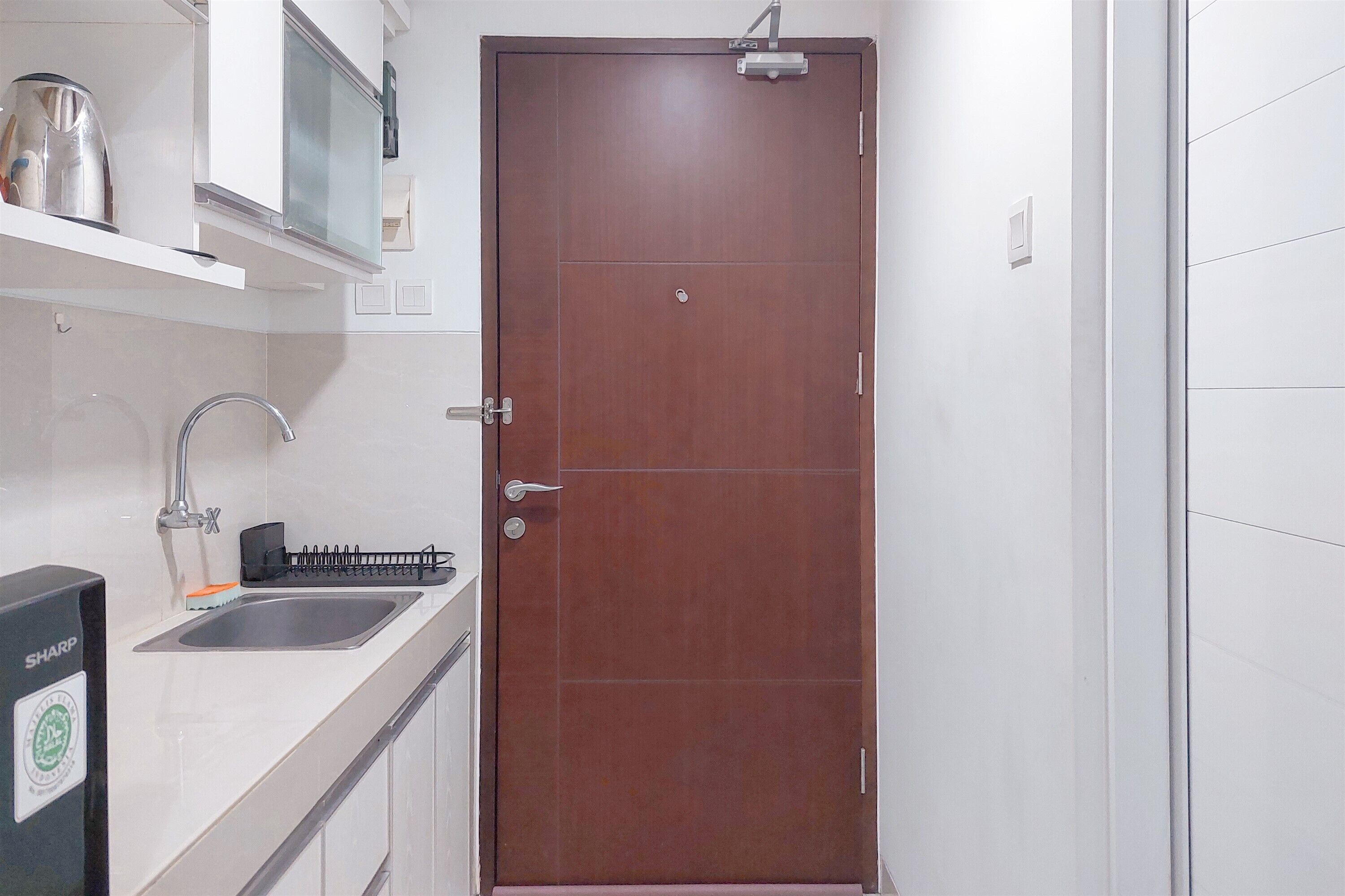 Una cocina con un lavamanos de acero inoxidable, un microondas y un armario sobre la encimera.