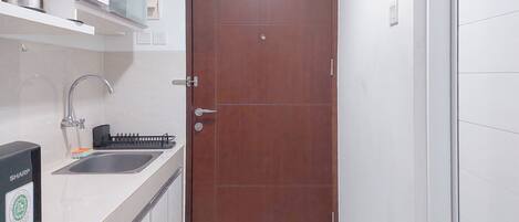 Una cocina con un lavamanos de acero inoxidable, un microondas y un armario sobre la encimera.