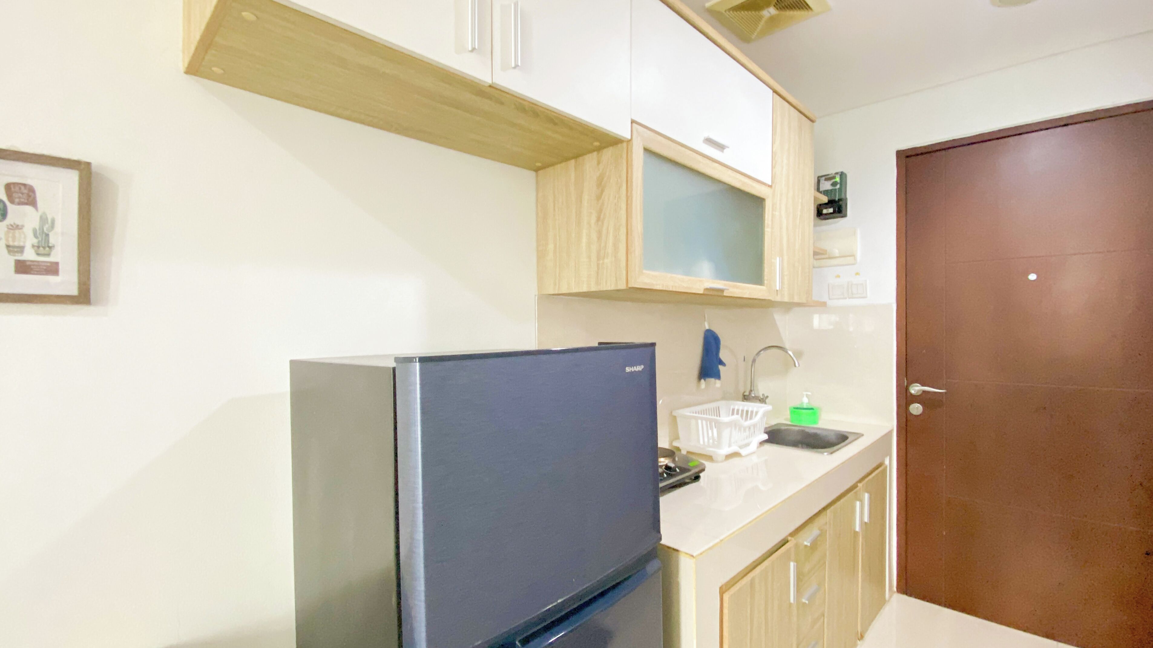 Una cocina pequeña con un refrigerador, un lavamanos y armarios de madera.
