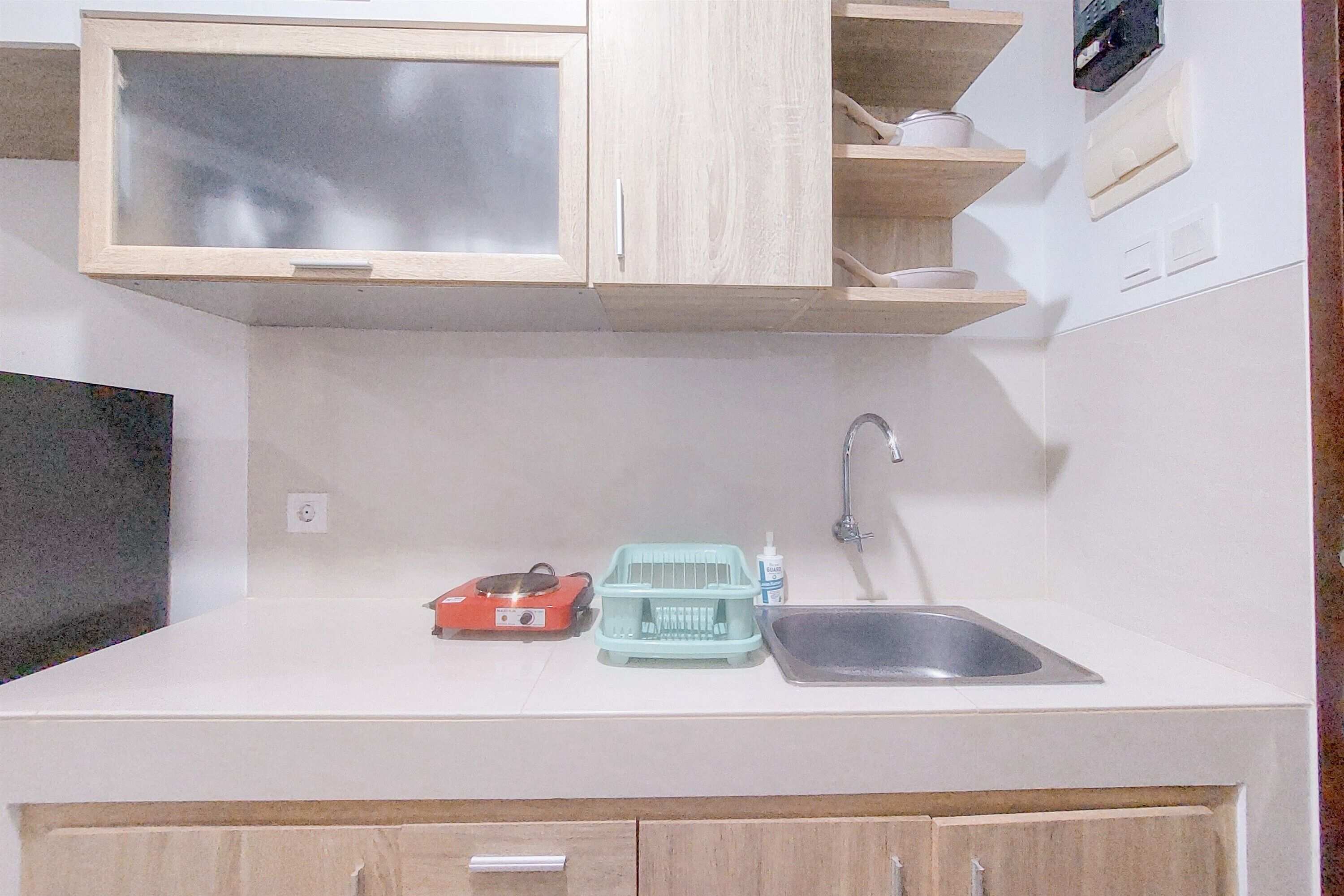 A compact kitchen with a sink, a dish rack, and a small appliance.