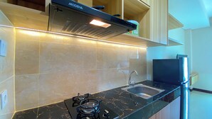 Een moderne keuken met een gasfornuis, een roestvrijstalen spoelbak en een zwarte afzuigkap.