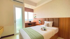 Een hotelkamer met een bed, een bureau en een raam met uitzicht op de stad.