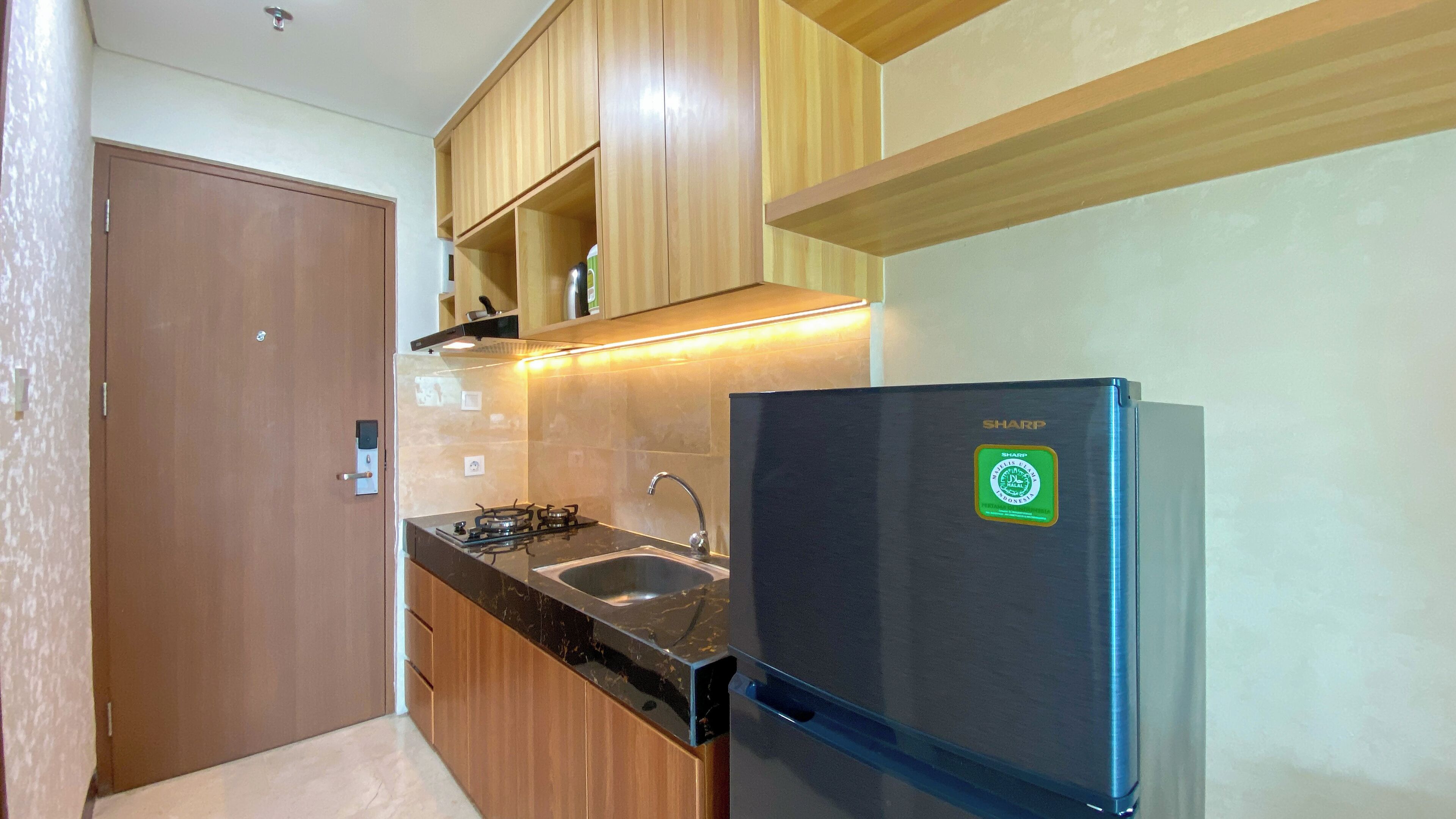 Una cocina compacta con armarios de madera, un refrigerador negro, una estufa a gas y un lavamanos.