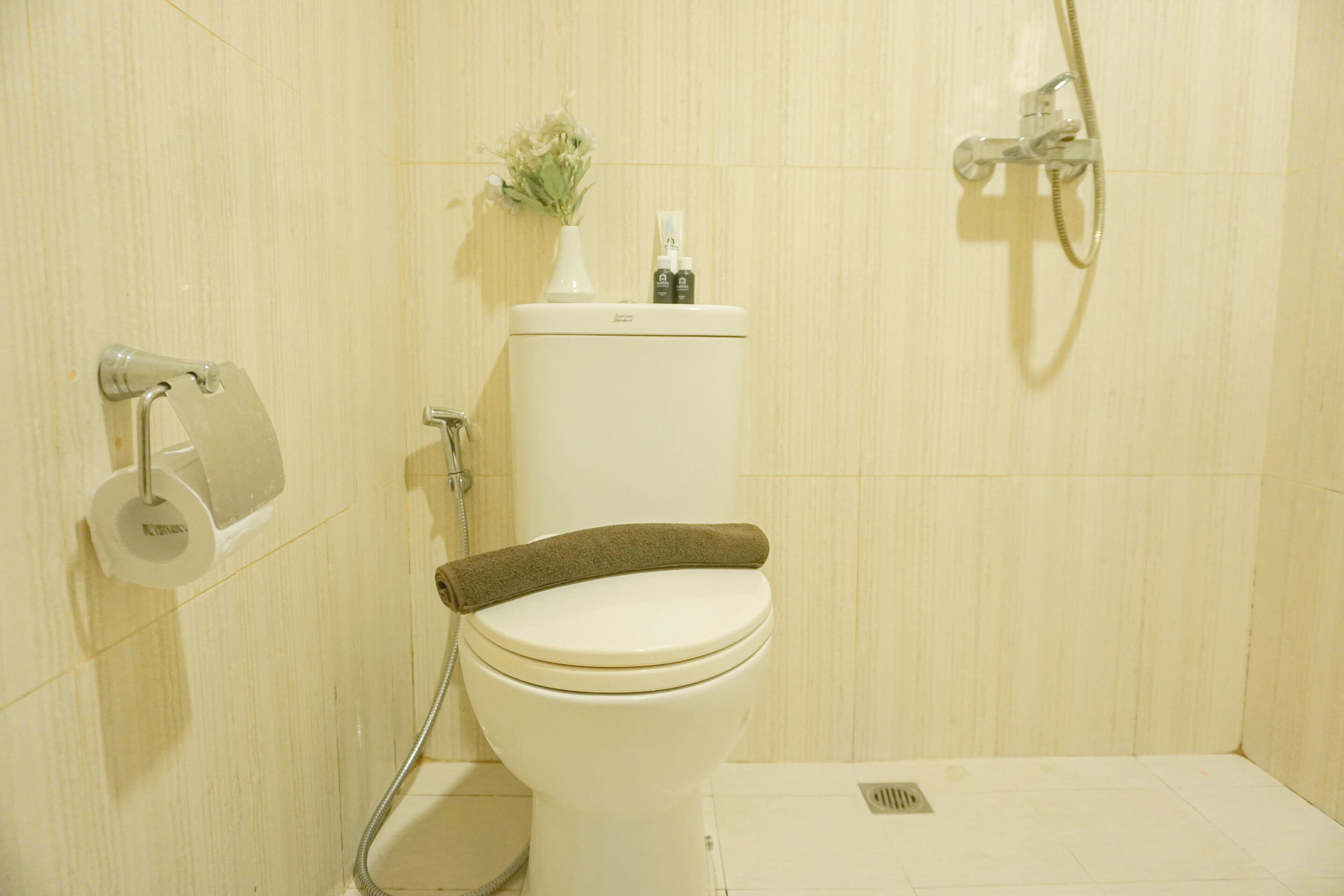 A bathroom with a toilet, a shower, and a toilet paper holder.