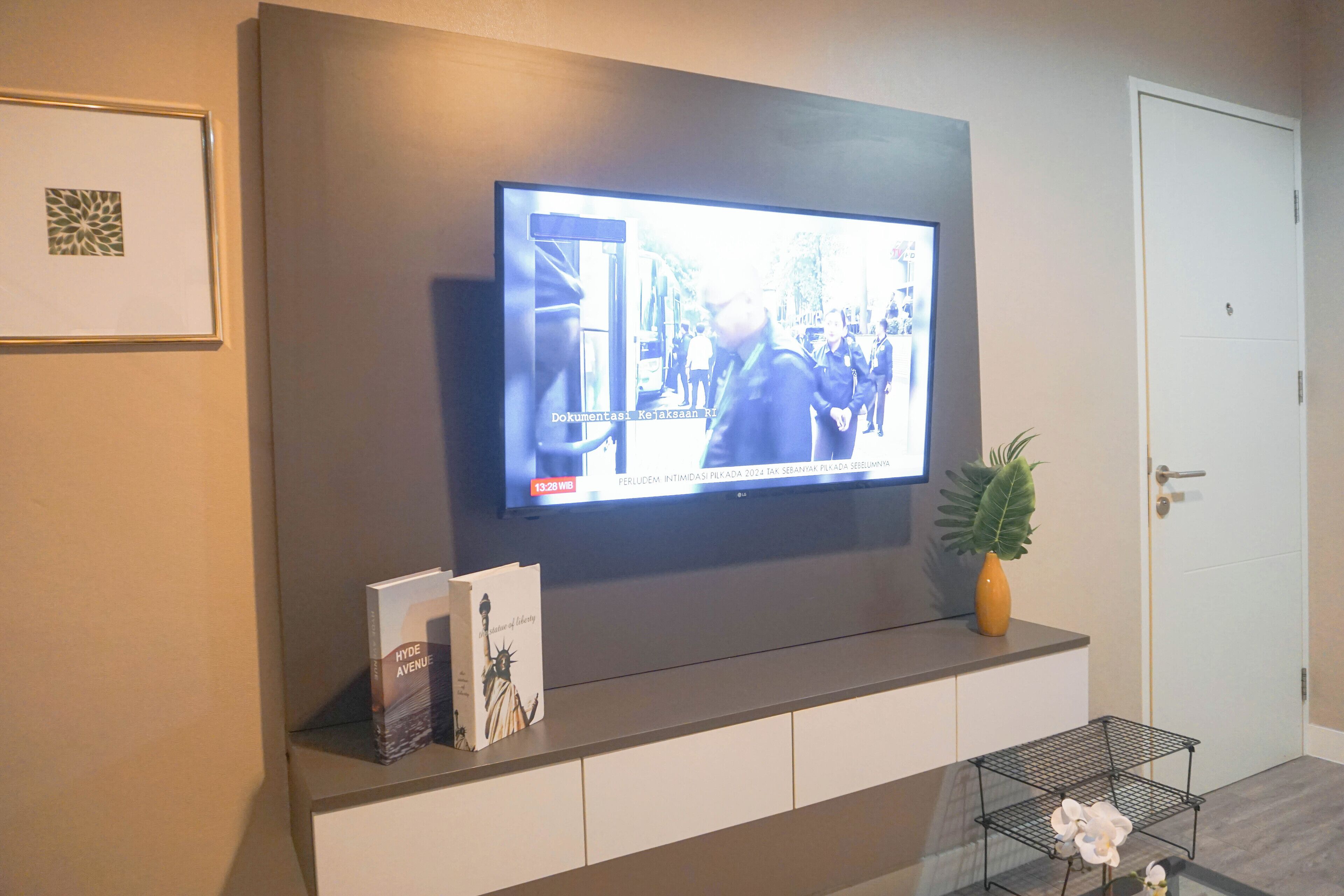 A television mounted on a wall displaying a news broadcast.