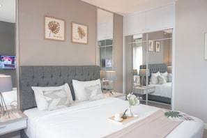 A modern bedroom with a large bed, bedside tables with lamps, a wardrobe, and two framed leaf art pieces on the wall. - Cozy and Spacious 2BR at Sentul Tower Apartment (Citaringgul)