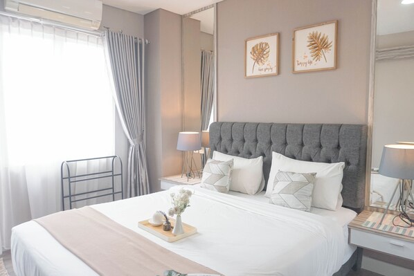 Una camera d'albergo ordinata con un letto grande, un comodino con una lampada, uno specchio e due quadri appesi al muro.