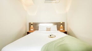A neatly made bed with white bedding and a green throw, flanked by two bedside tables with wall-mounted lamps. - Stunning and Well Designed 2BR Apartment at Vittoria Residence (Jakarta)
