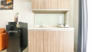 A compact kitchen with a black refrigerator, a stove, and wooden cabinets. - Stunning and Well Designed 2BR Apartment at Vittoria Residence (Jakarta)