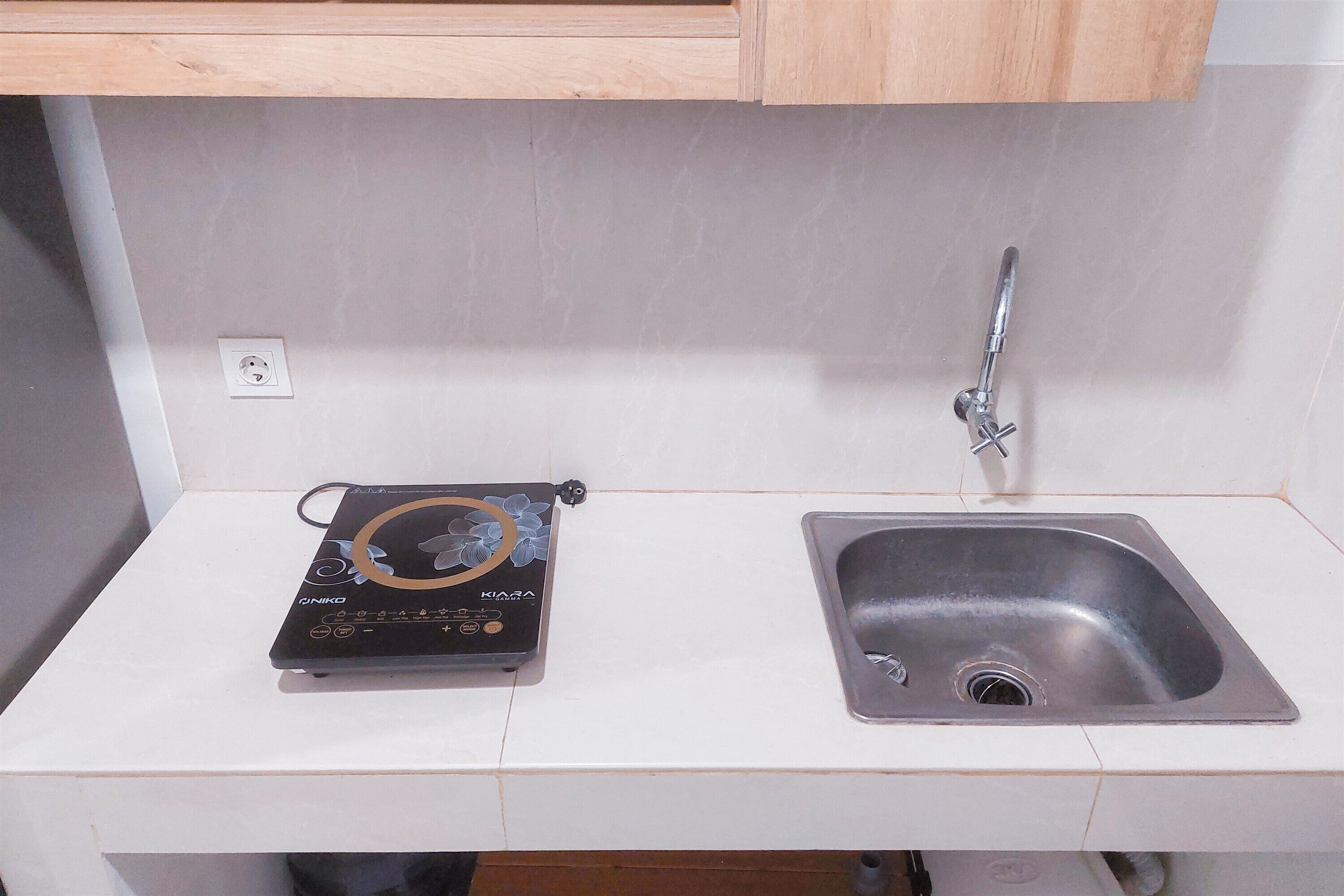 A kitchen with a built-in sink, a countertop, and a Ginko brand electric kettle.