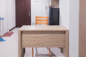 Eine kleine Küche mit einem Holztisch, einem Stuhl und einem Kühlschrank.