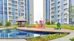 A residential building with a swimming pool, a children's play area, and a gazebo. - Spacious and Homey 2BR at Podomoro City Deli Medan Apartment (Medan)
