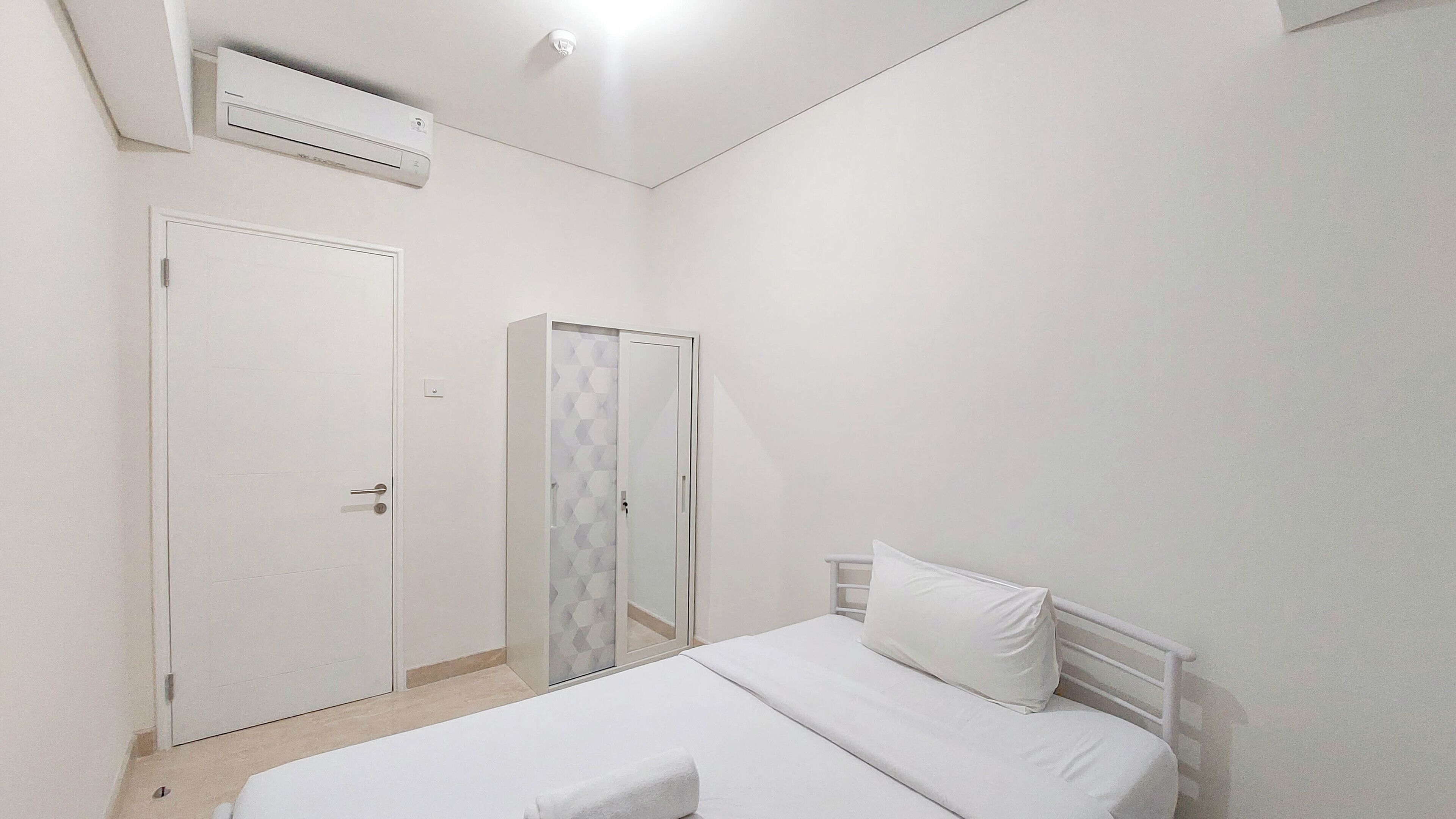 A bedroom with a bed, a wardrobe, and an air conditioning unit.
