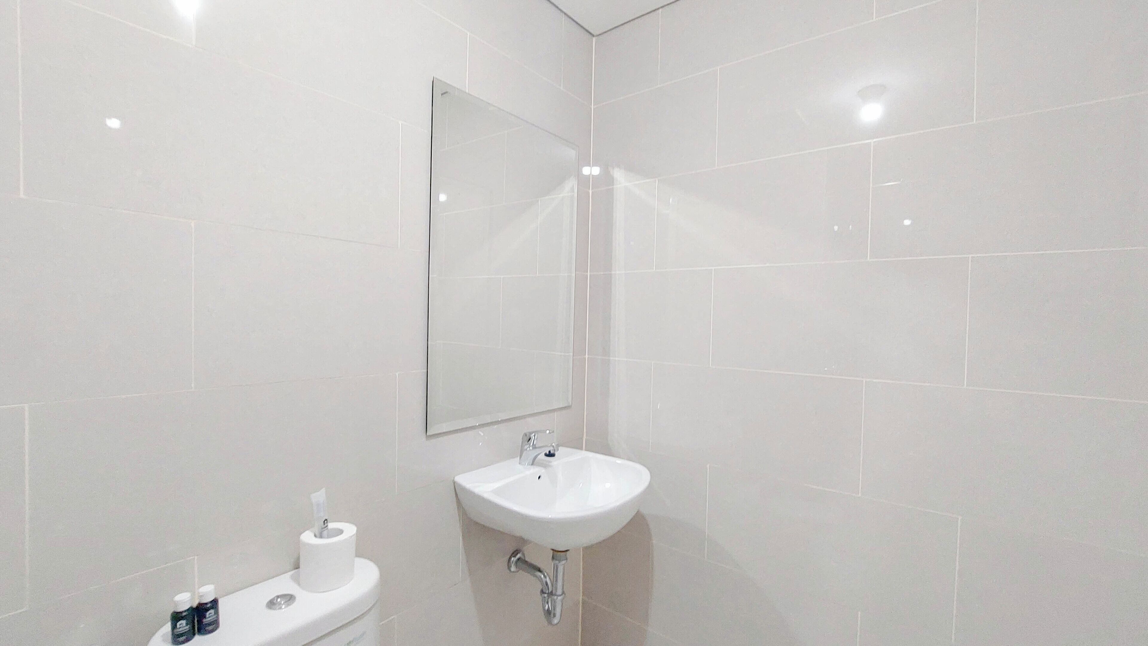 A bathroom with a white sink, a toilet, and a mirror.