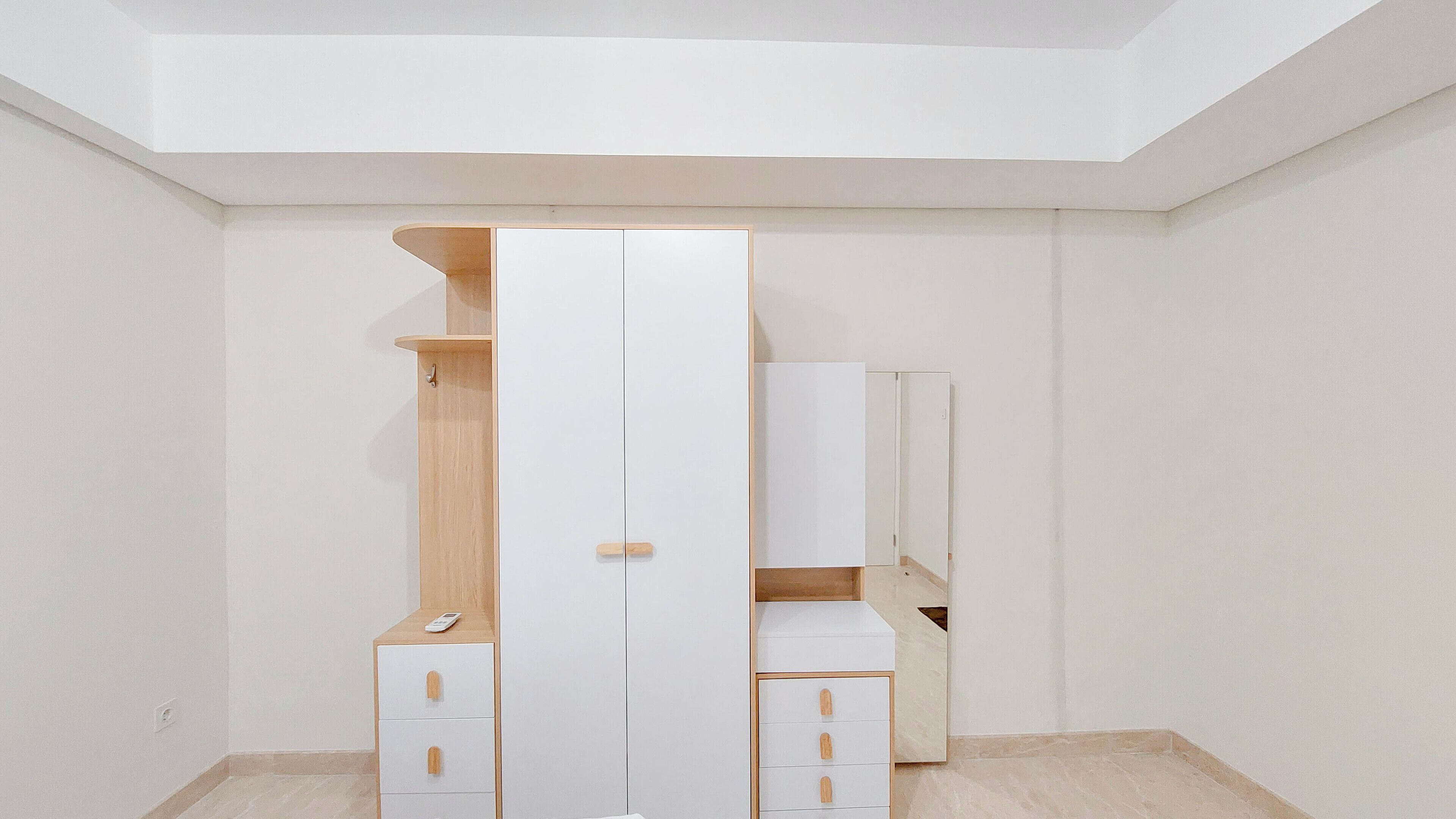 Une pièce au décor minimaliste, avec une armoire blanche, une étagère en bois et un meuble avec des portes miroir.