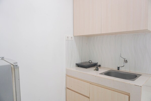 A small kitchen with a sink, a countertop, and cabinets. - Cozy Living 1BR at Sentul Tower Apartment (Citaringgul)