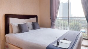 A neatly made bed with a headboard, pillows, and a bedside table with a lamp and papers. - Cozy and Homey Studio Apartment at Springwood Residence Tangerang (Tangerang)