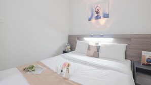 A hotel room with a neatly made bed, a bedside table with a book, and a wall-mounted air conditioner. - Best Deal and Stunning 2BR Apartment at Vittoria Residence (Jakarta)