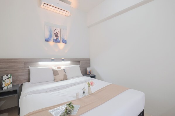 Ein ordentlich eingerichtetes Hotelzimmer mit Bett, Nachttischen und einer Wand-Klimaanlage.