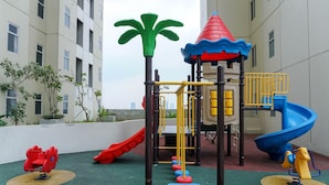 A children's playground with slides and climbing structures, surrounded by buildings. - Well Designed and Warm 2BR Apartment at Vittoria Residence (Jakarta)