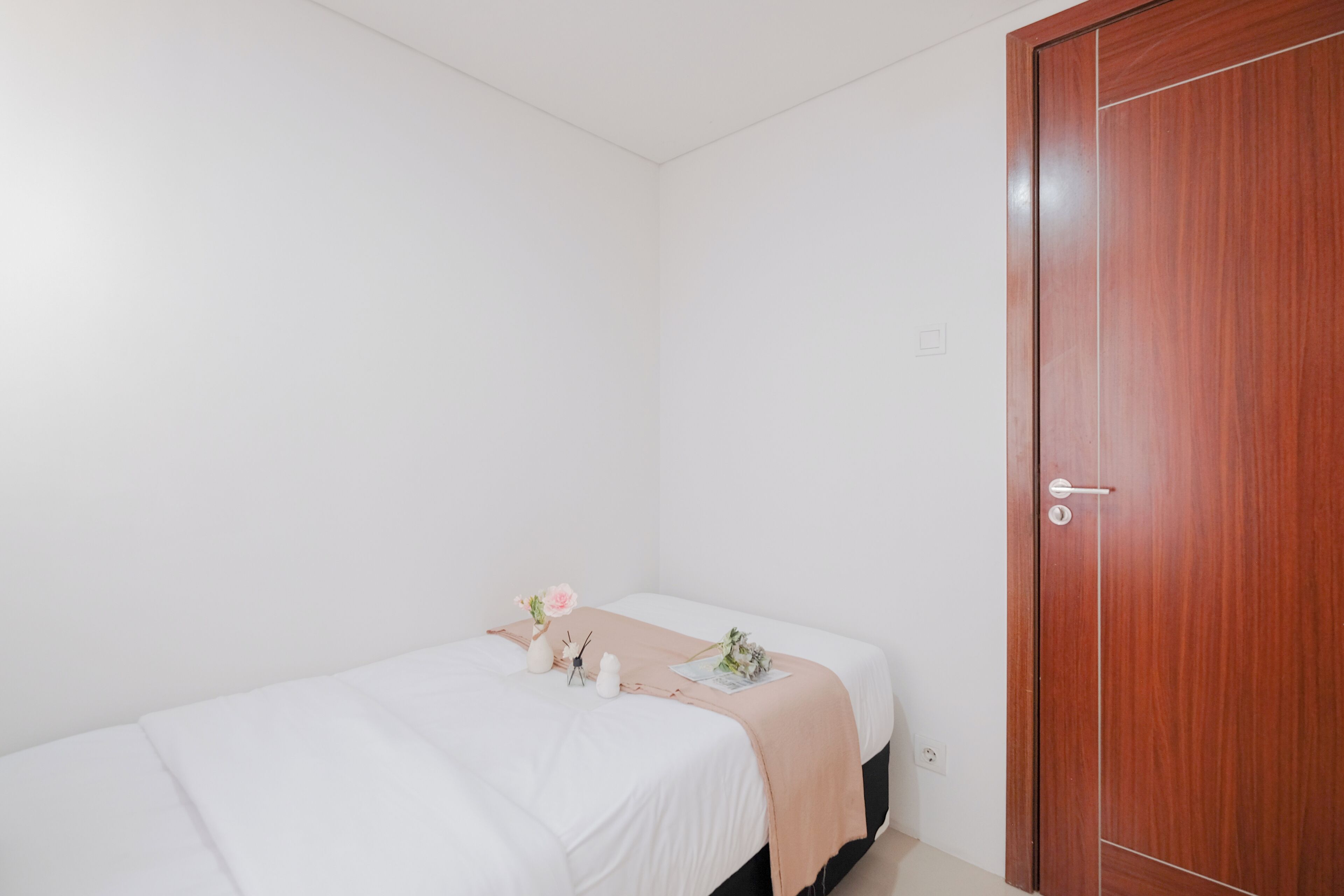 A small, neatly arranged bedroom with a single bed, a wooden wardrobe, and minimal decor.