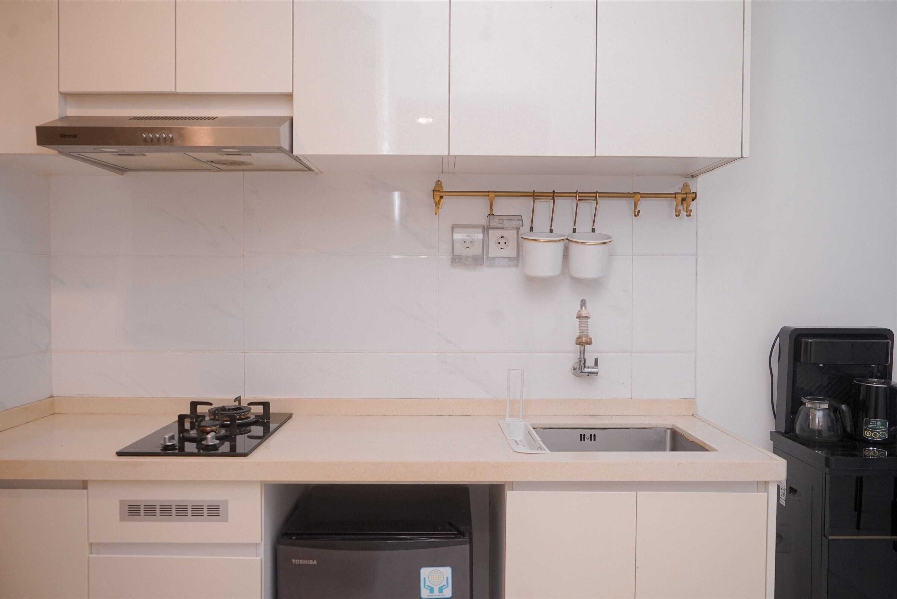 A modern kitchen with white cabinets, a stainless steel range hood, a dishwasher, and a coffee machine.