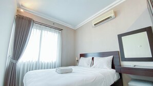 Una camera d'albergo con un letto, una scrivania, uno specchio e un condizionatore d'aria.