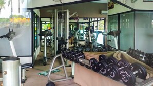 Una palestra con attrezzature per esercizi, tra cui manubri, tapis roulant e macchinari per pesi.