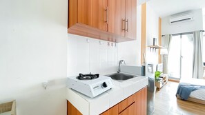 Compact kitchenette with gas stove, sink, and modern cabinetry.