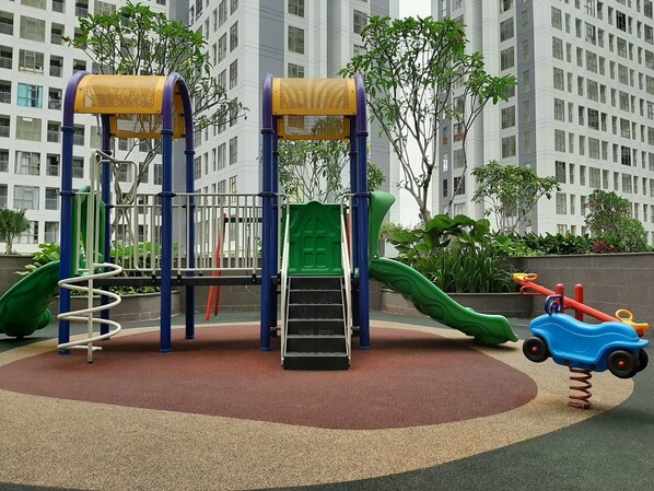 Children can play and climb on the multi-level frame with a slide and a small vehicle.