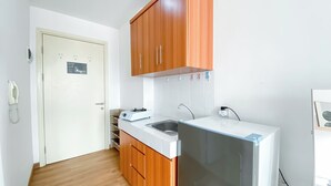 Eine kleine Küche mit Holzausstattung, einem integrierten Spülbecken und einem kompakten Kühlschrank.