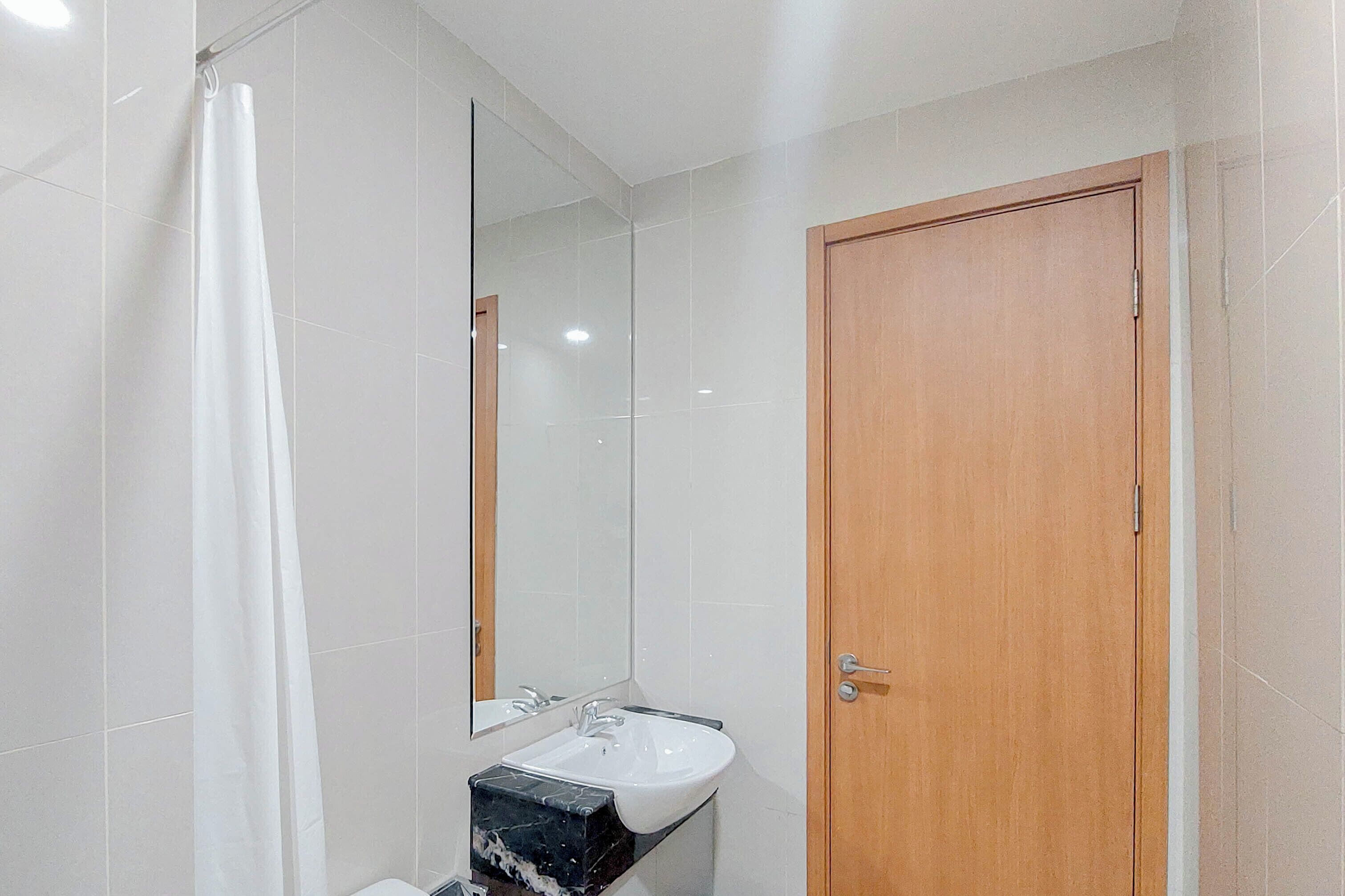 Uma casa de banho com uma pia branca, um espelho e uma porta de madeira.