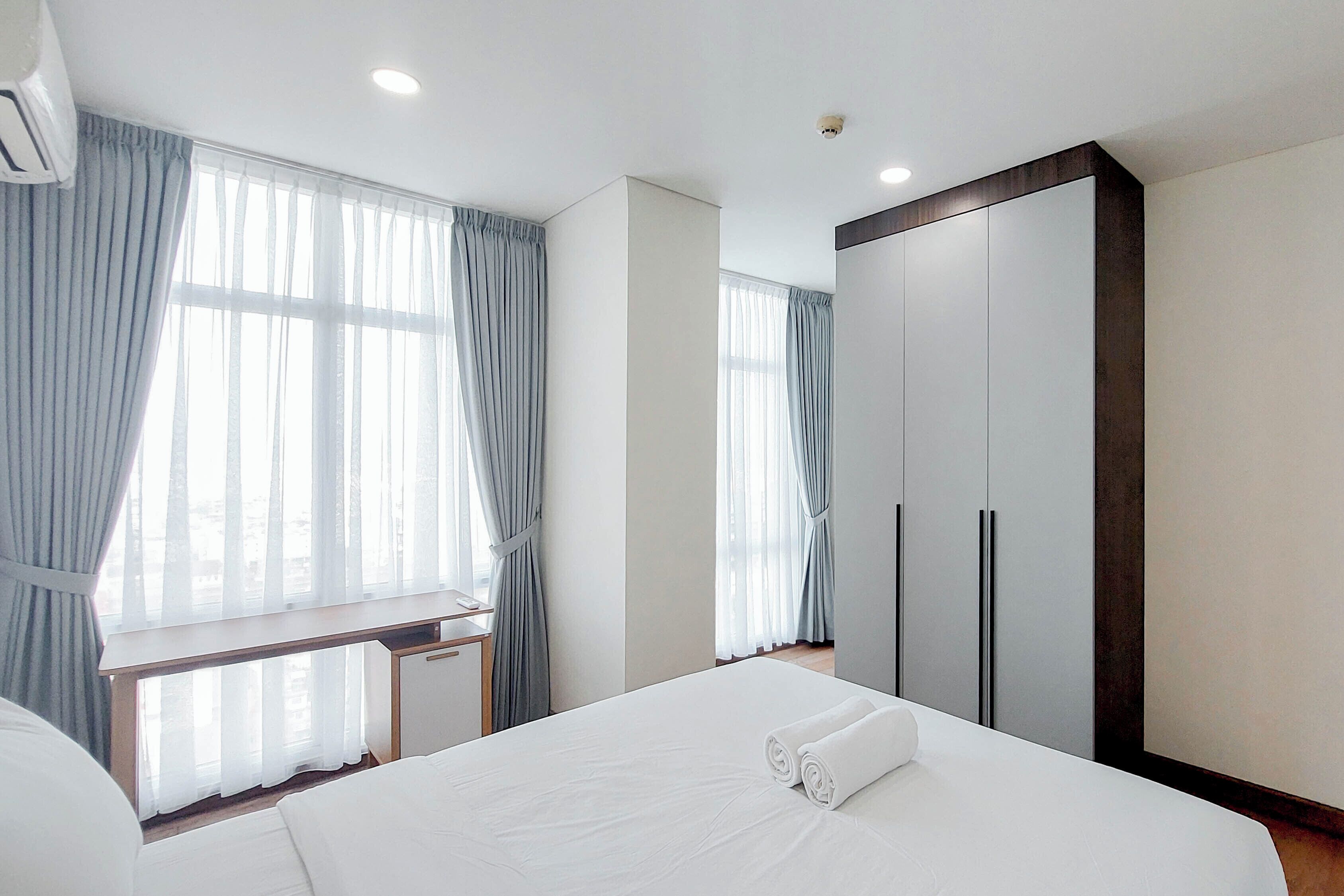 A hotel room with a bed, a desk, and a wardrobe.