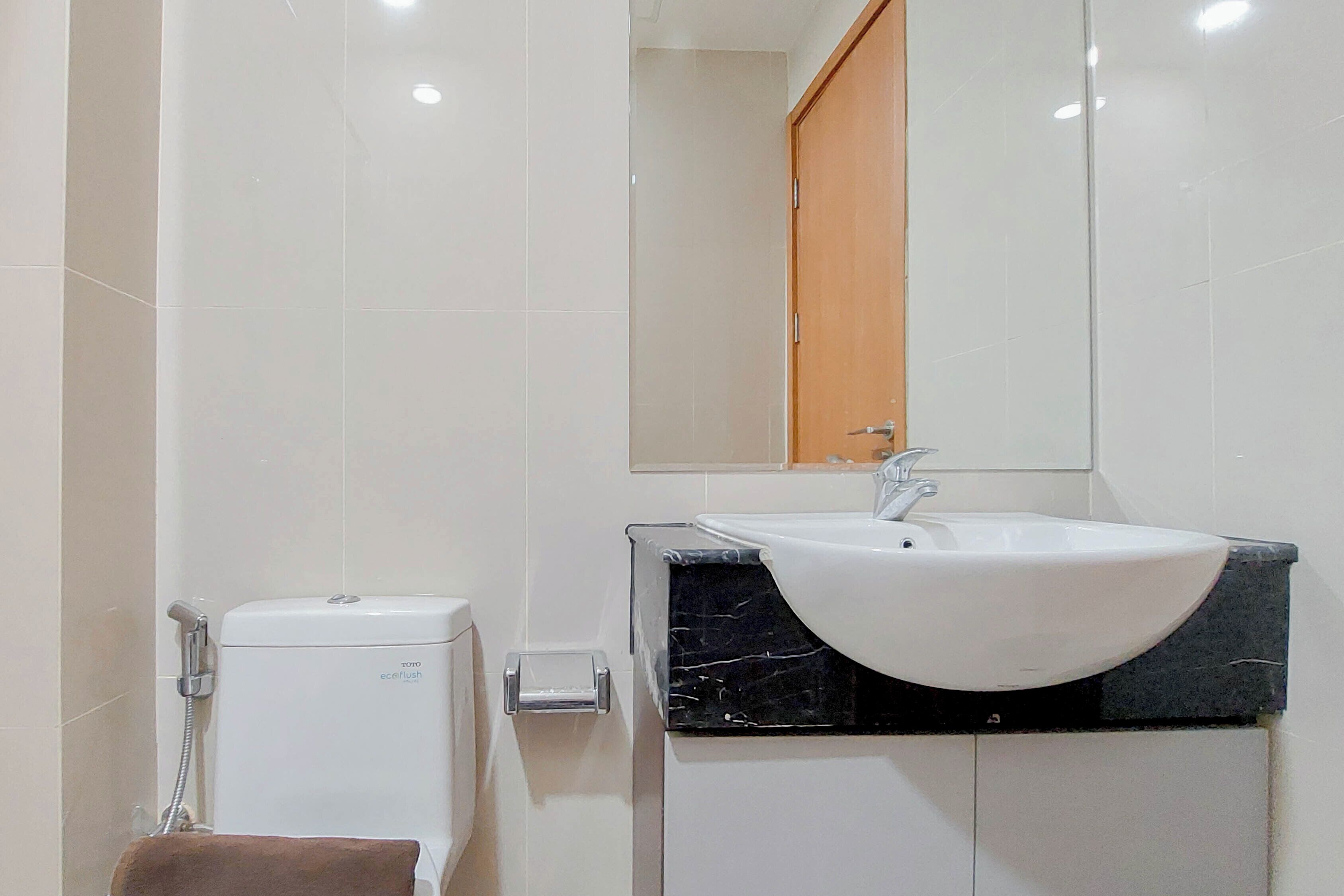 A bathroom with a white toilet, a sink with a black countertop, and a mirror above the sink.