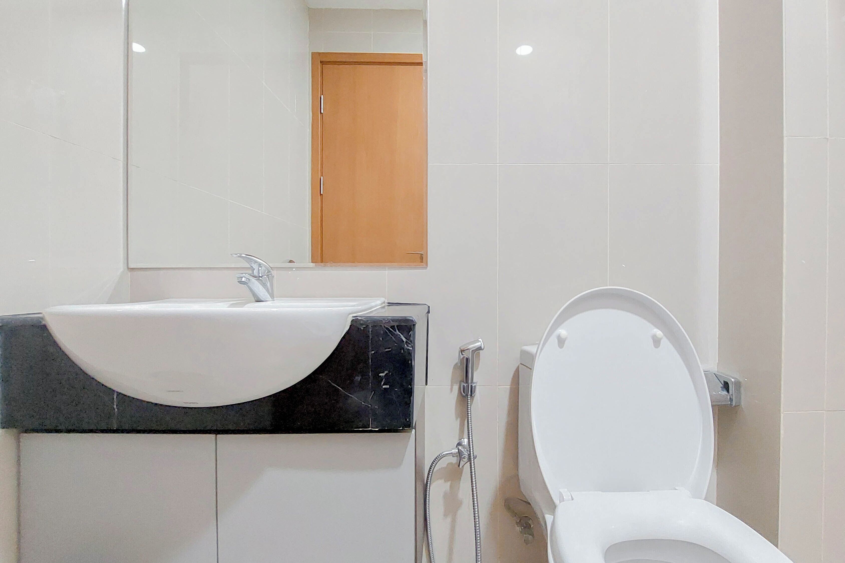 Une salle de bain avec un lavabo blanc, un miroir et des toilettes.