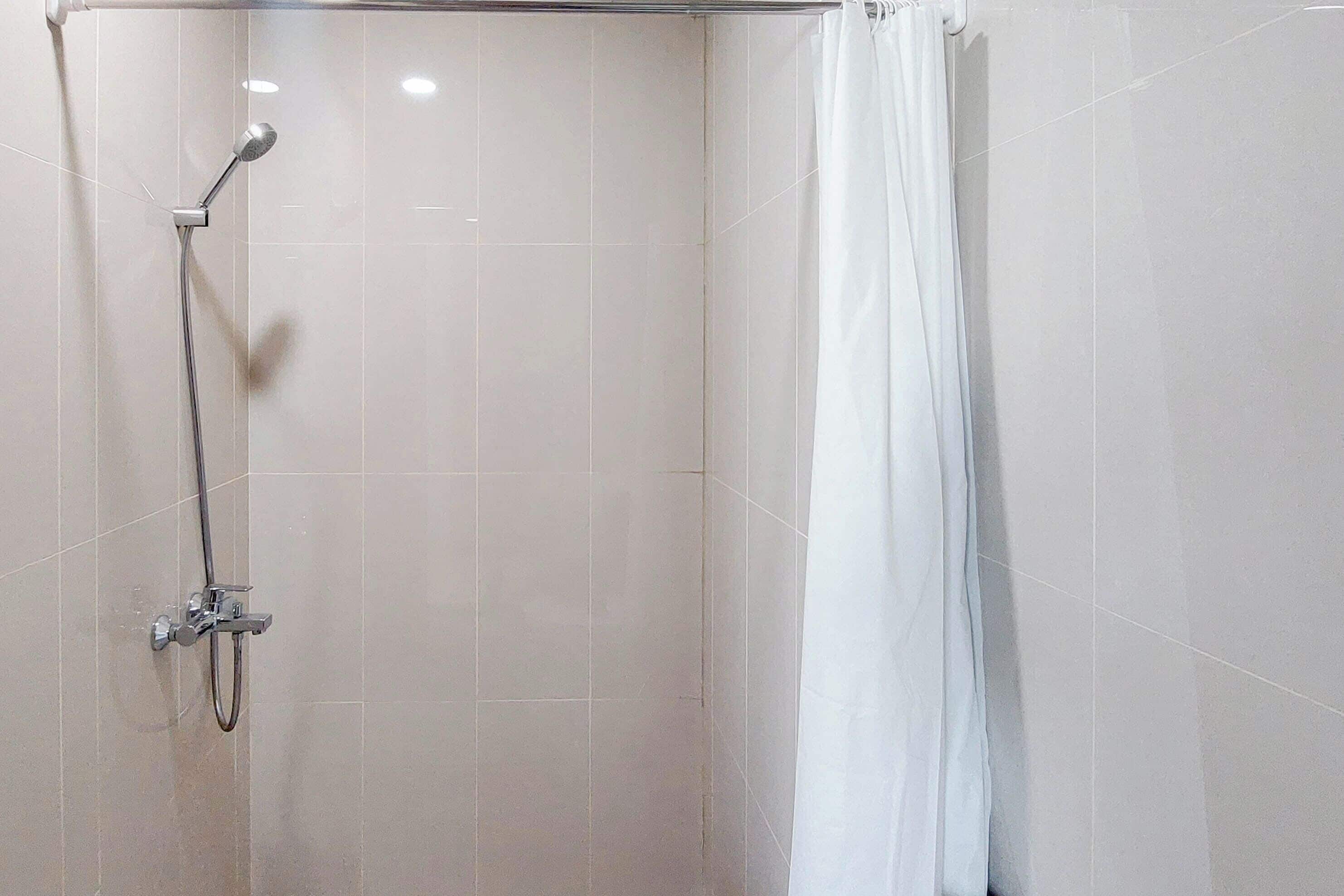 Un área de ducha con puerta de vidrio, alcachofa y cortina.