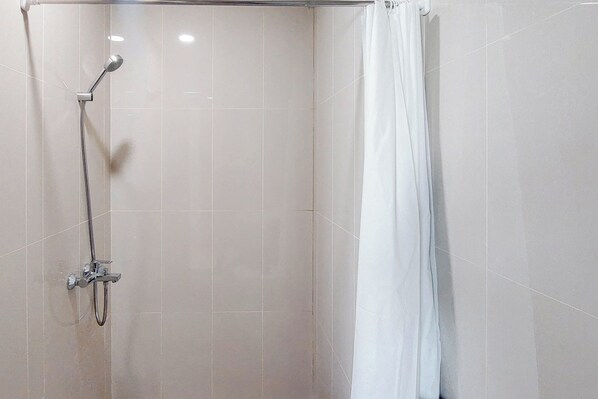 Un espace douche doté d’une porte en verre, d’un pommeau de douche et d’un rideau.