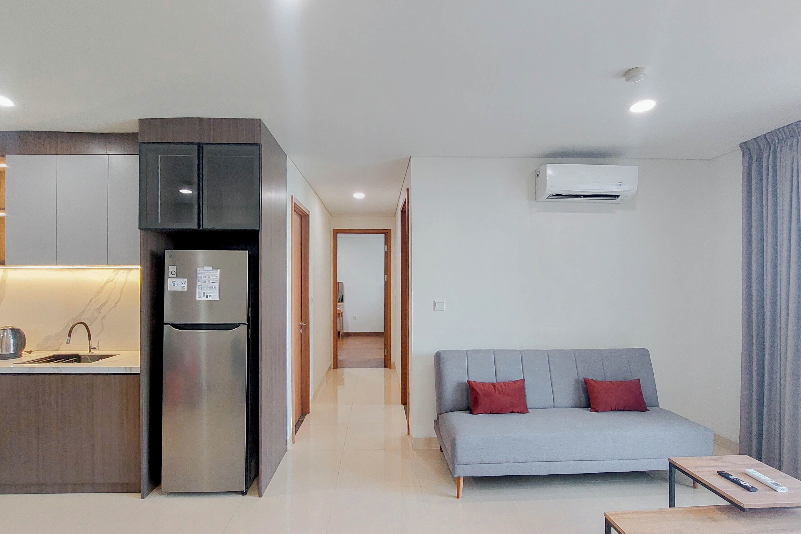 A modern apartment with a kitchen, a grey sofa, and a small table.