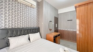 A hotel room with a bed, a bedside table, a mirror, and a wardrobe. - 1BR Modern Suites at Tamansari Prospero Sidoarjo Apartment (Sidoarjo)