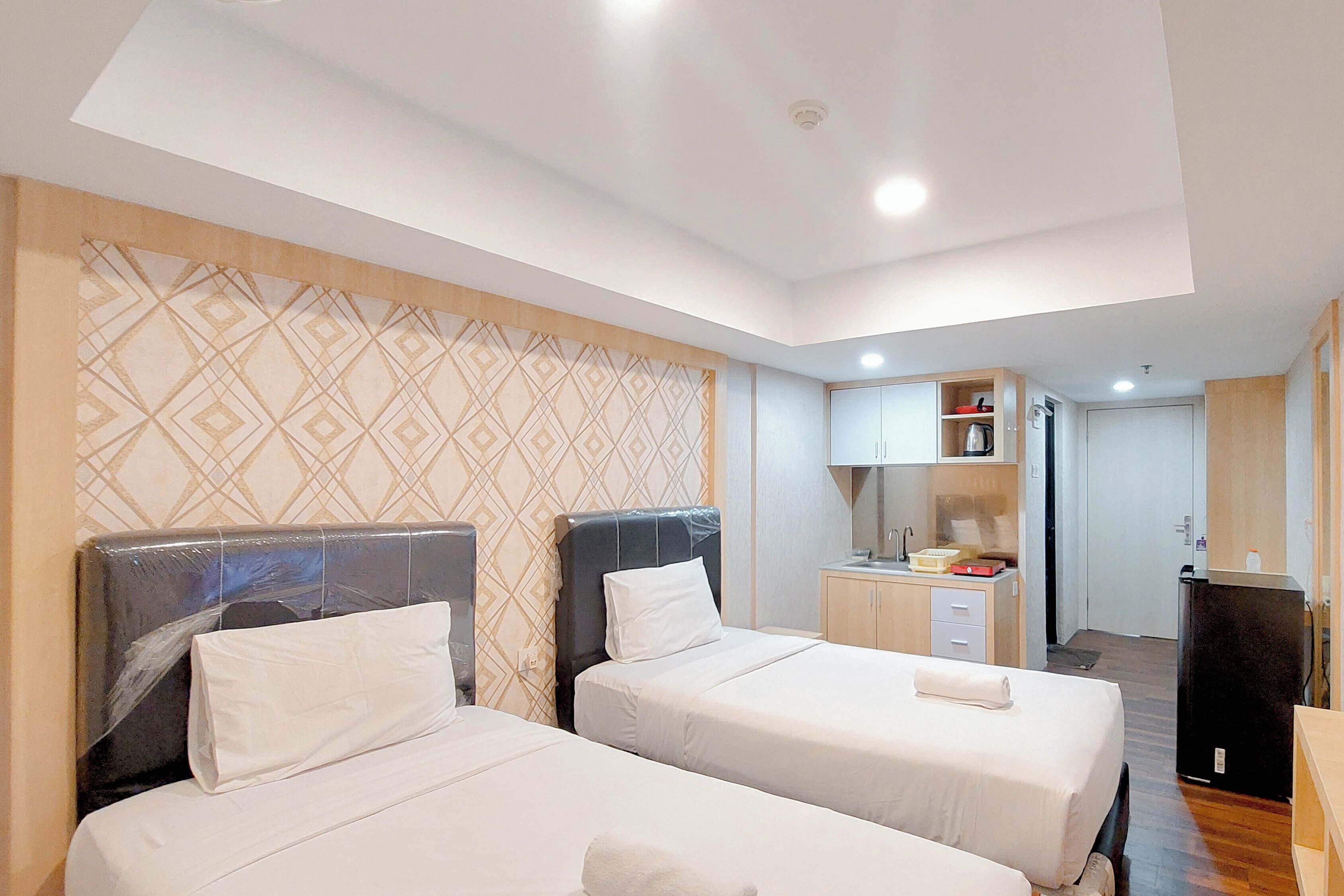 A hotel room with two beds, a kitchenette, and a bathroom.