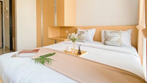 Una habitación de hotel con cama, una mesita de noche con un florero y una puerta a la izquierda.