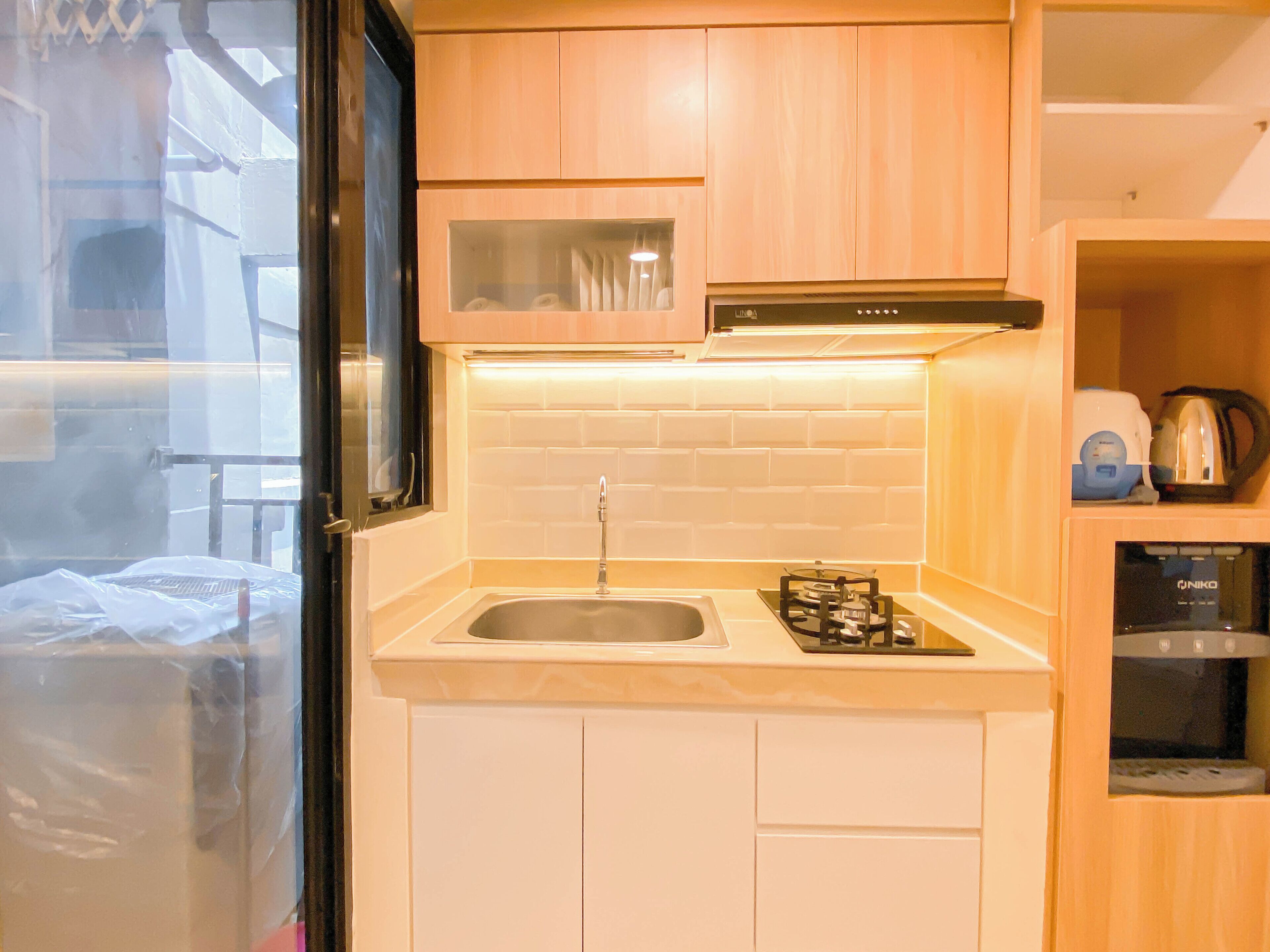 A compact kitchen with a gas stove, sink, and wooden cabinets.