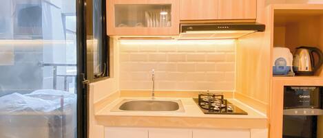 A compact kitchen with a gas stove, sink, and wooden cabinets.