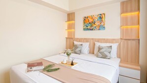 A modern hotel room with a large bed, a bedside table, a decorative painting, and built-in lighting. - Cozy Place and Tidy 2BR Apartment Meikarta (Cikarang)
