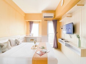 Une chambre d’hôtel moderne dotée d’un grand lit, d’un bureau, d’une télévision et d’un balcon avec des rideaux.