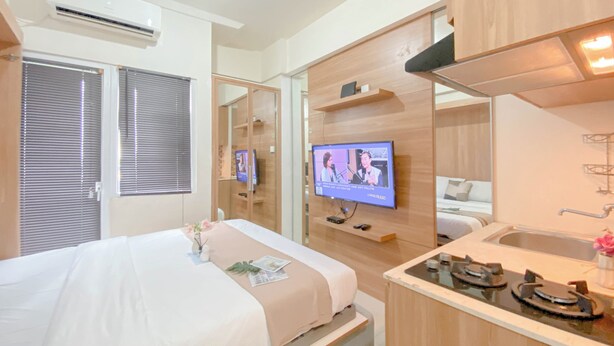 Ein modernes Hotelzimmer mit Bett, Fernseher und einer kleinen K üchenzeile.