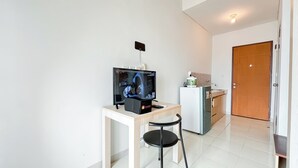 Un petit espace de vie moderne comprenant un téléviseur, une table, une chaise, un coin cuisine et une porte.